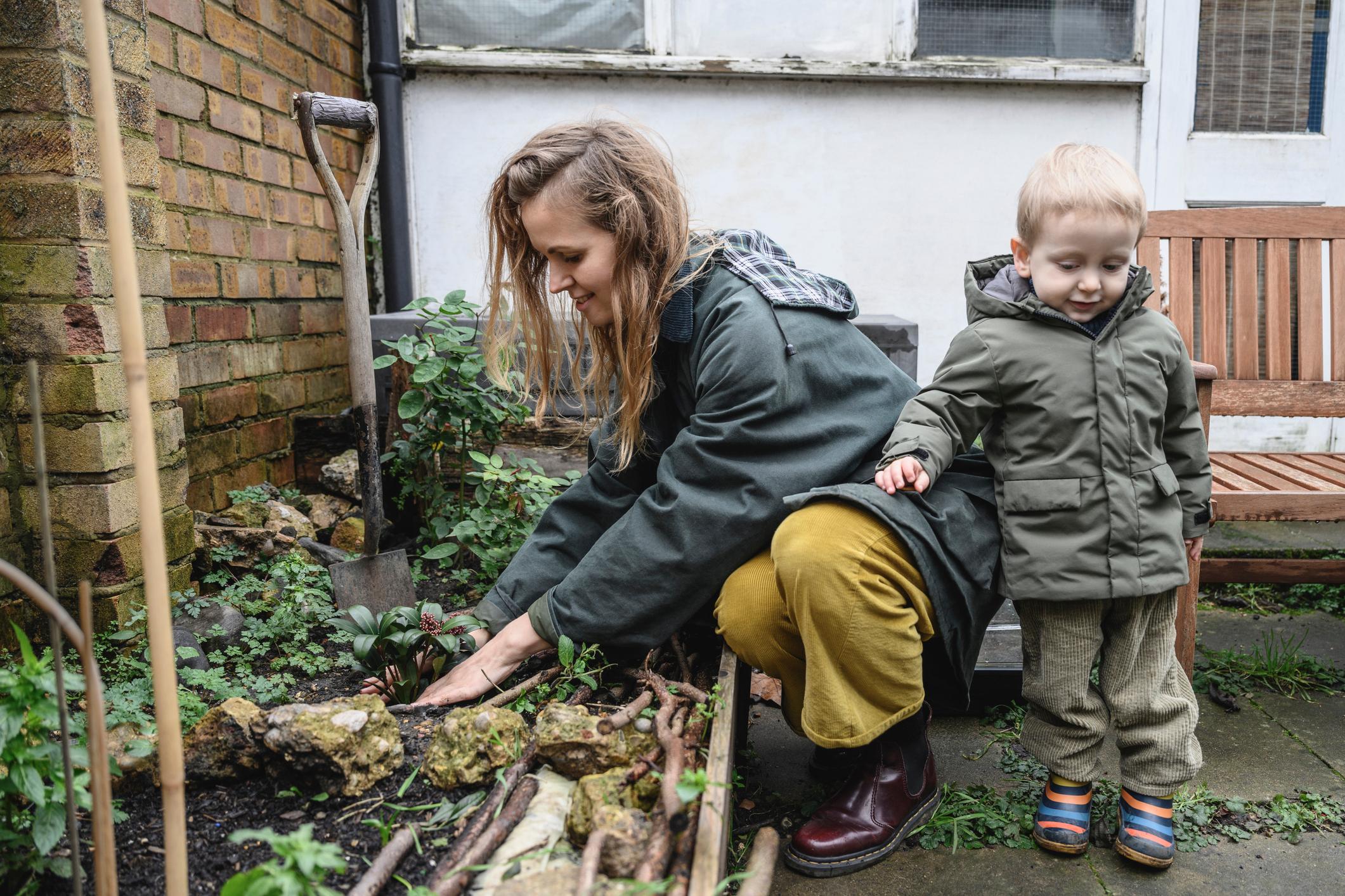 Full length view of mid 30s Caucasian woman and young son in warm clothing gardening together in anticipation of spring.